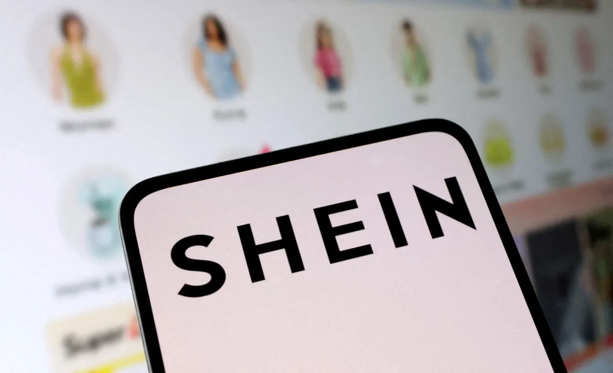 Close-up of a smartphone screen displaying the large black logo for the fashion company SHEIN, suggesting online shopping in Canada.